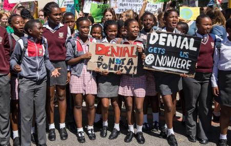 South African school children hold placards denouncing climate crisis denialism.