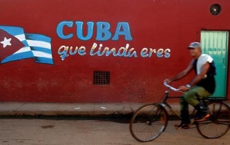 Cuban bicycle rider passing a mural