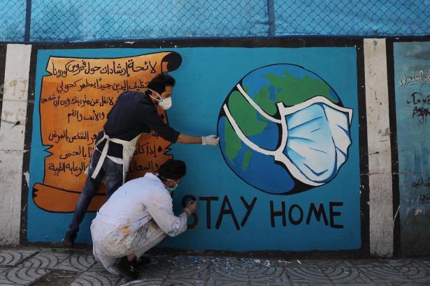 Palestinian artists paint a mural on a wall in Gaza. 