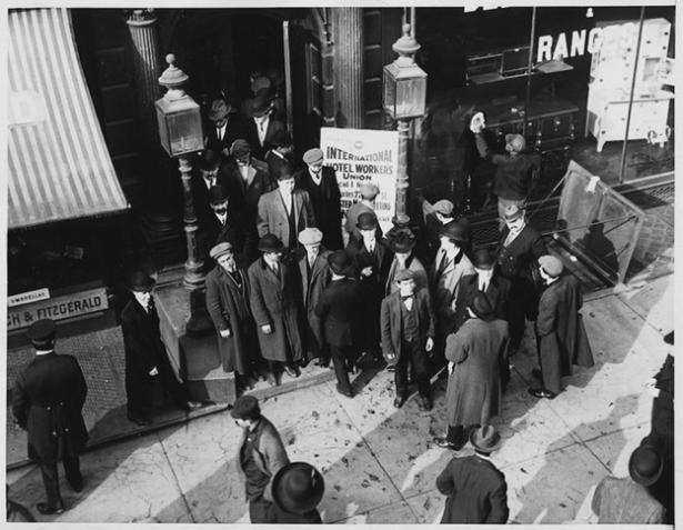 Photo of men in suits and coats standing in front of the union building. 