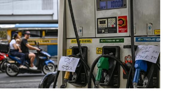 Photo of a gas pump with a sign "out of stock" on a busy street. 