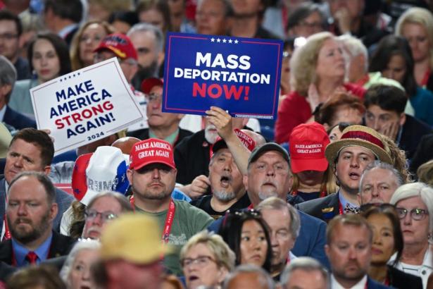 Photo of a Trump rally with people holding "Mass Deportation Now" signs.