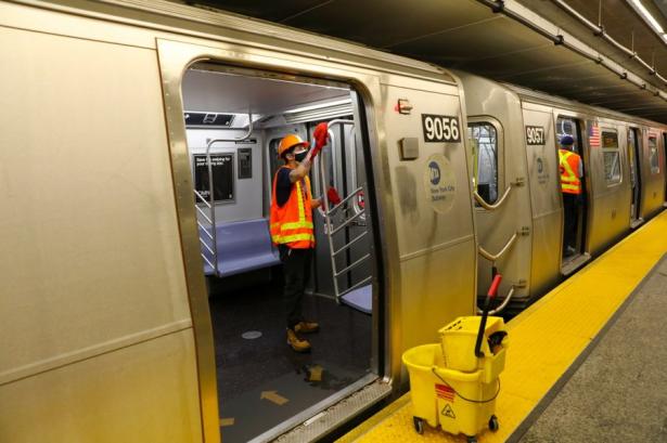 Photo of a subway from the platform with the door open with a transit worker cleaning. nOhiti