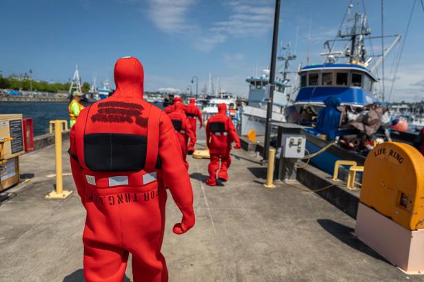 Photo of the backs of suited safety worker walking along a dock.