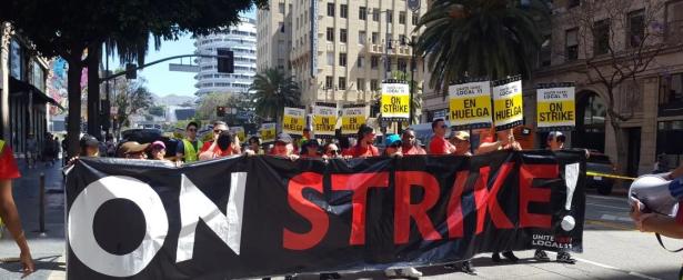 Unite Here strikers marching with a ON STRIKE banner