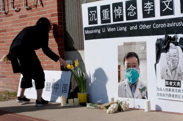 Women places a flower next to a photo of  Dr. Li Wenliang  