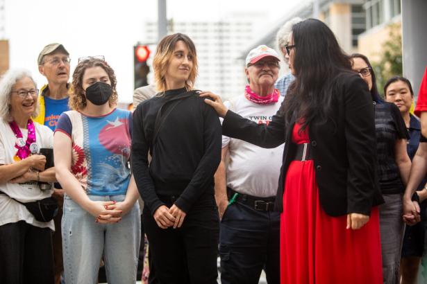 Photo of people standing behind a speaker at a press conference. 