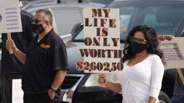 Two protesters holding signs.  In the foreground one reading "My Life is Only Worth kth Wo 