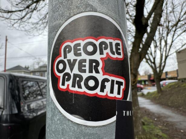 Photo of a sign on a post that says PEOPLE OVER PROFIT