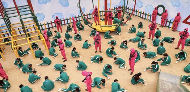 Scene from the Netflix show:  Individuals in green outfits kneeling on the floor.