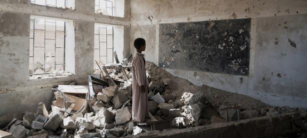 A Yemeni student stands in the ruins of his former classroom. 