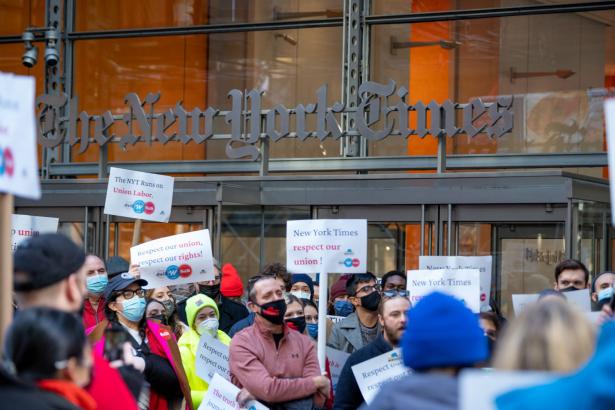 Workers with signs rallying in front of the NYTimes