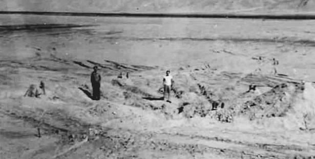 Two men standing at ground zero after the first nuclear bomb test