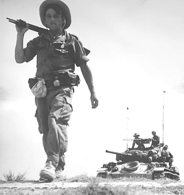 French soldier on foot in Vietnam in front of a U.S.-supplied tank