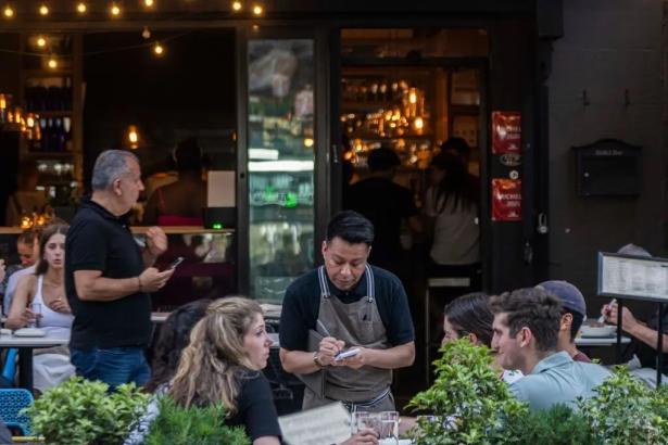 Waiter taking peoples' orders at table in a restaurant.