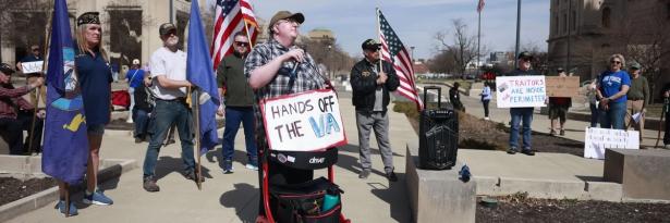 Photo of people marching with signs like, "Hands off the VA". 