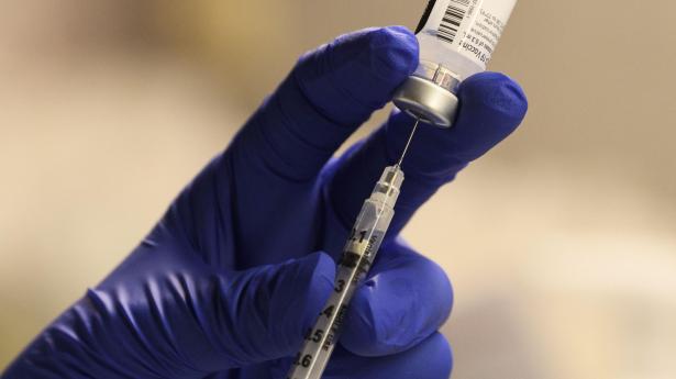 A pharmacist fills a syringe to prepare a dose of vaccine for front-line health care workers in Torrance, CA. 