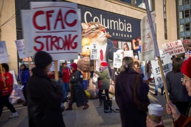People picketing with signs reading "on strike" in front of Columbia College in Chicago.