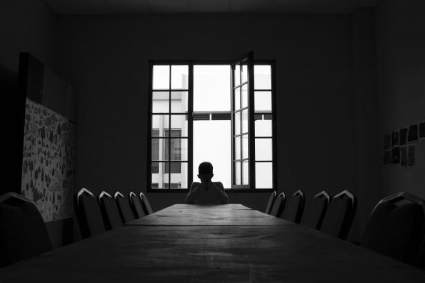 A person sitting alone at a desk in the dark.
