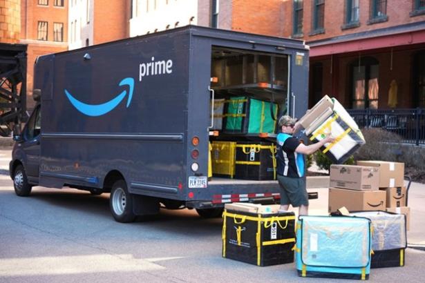 Photo of an Amazon truck getting loaded in the back end by workers. 