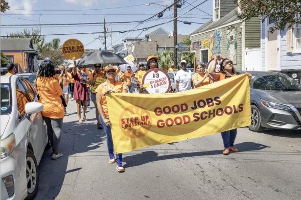 March behind a banner that says:  Good Jobs Good Schools