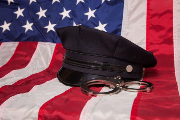 USA flag with cop hat and handcuffs