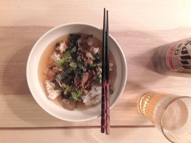 A bowl filled with dashi, rice, seaweed, and other Japanese ingredients. Next to the bowl is a can of the Japanese beer, Asahi.