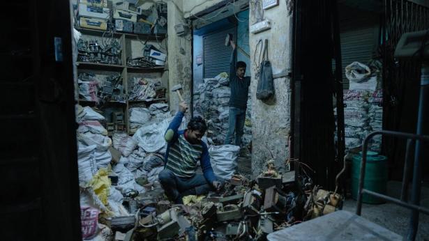 photo of workers in a room piled high with bags of discarded electronic waste. 