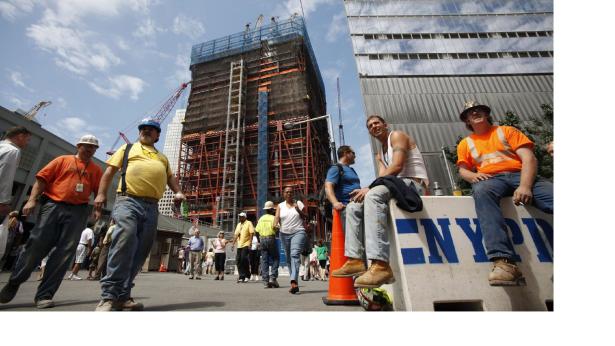 men in hardhats in front of a building in some states of being built