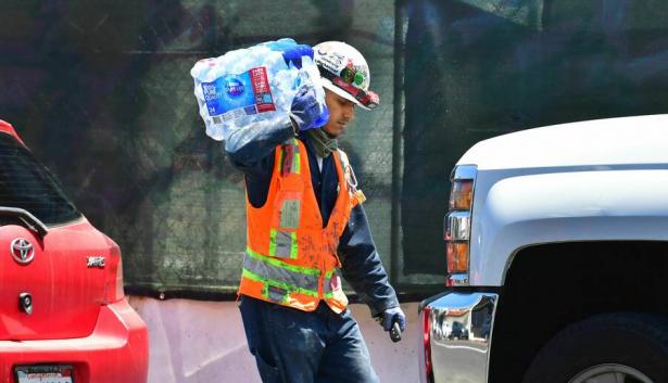 Worker carrying a block of ice to a truck.