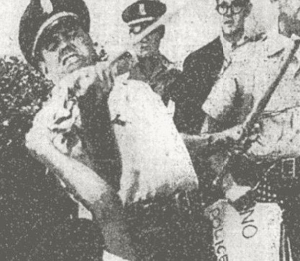 Uniformed police officer wrestles a U.S. flag from a 5-year-old picketer