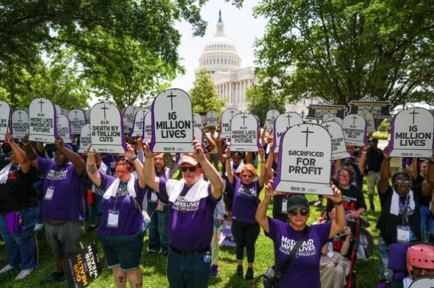 Protestors holding up cardboard signs the shape of a gravestone which reads sacrificed for profits and the like.