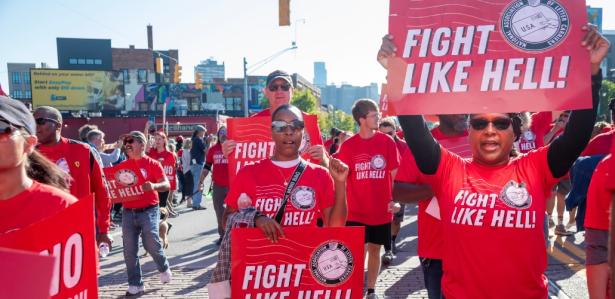 Photo of people marching in red tees and holding signs that say fight like hell 