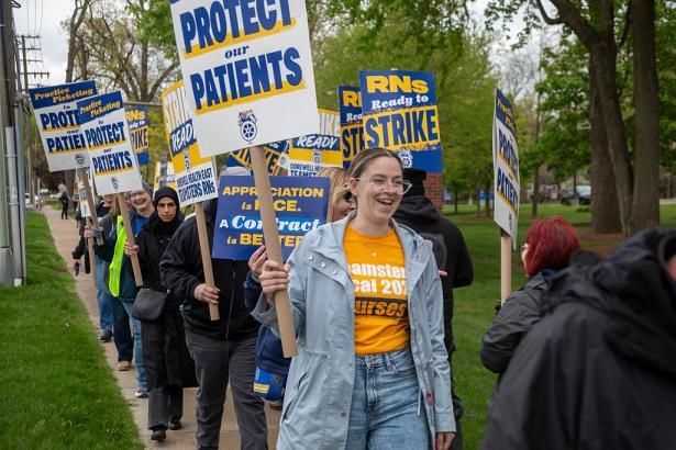 photo of a line of workers with signs such as Protect Our Patients.