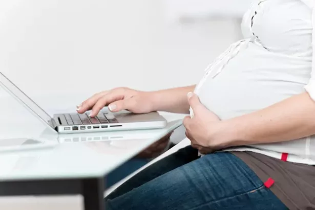 photo of the torso of a pregnant women a desk. 