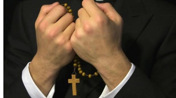 photo of the hands of a priest with a rosary  