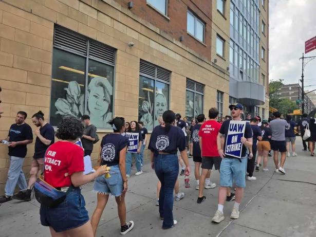 Photo of people on a picket line with signs that say UAW on strike