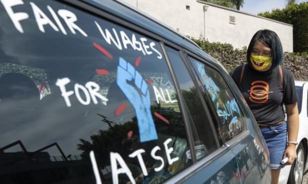 A woman standing behind a van with the following painted on the window:  Fair wages for IATSE