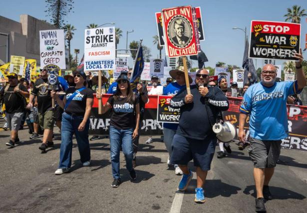 Photo at the front of a march going forward with signs reading Teamsters against fascism.