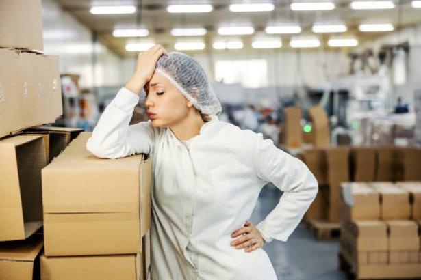 Worker resting on a box in a warehouse.