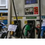 Photo of a gas pump with a sign "out of stock" on a busy street. 
