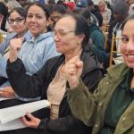 Photo of a group of women seated with raised fists.