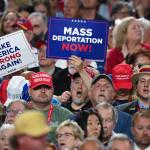 Photo of a Trump rally with people holding "Mass Deportation Now" signs.