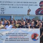 Photo of a group of French dockworkers with raised fists and a banner in support of a Swedish dockworker  