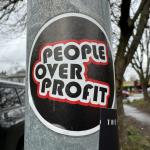 Photo of a sign on a post that says PEOPLE OVER PROFIT