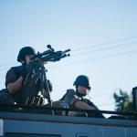 A police sniper atop a Special Weapons and Tactical vehicle.