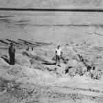 Two men standing at ground zero after the first nuclear bomb test