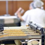 Cookies on a conveyor belt with workers in the background