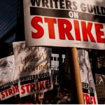 Placards reading writers guild on strike being help by picketers. 