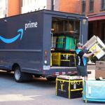 Photo of an Amazon truck getting loaded in the back end by workers. 